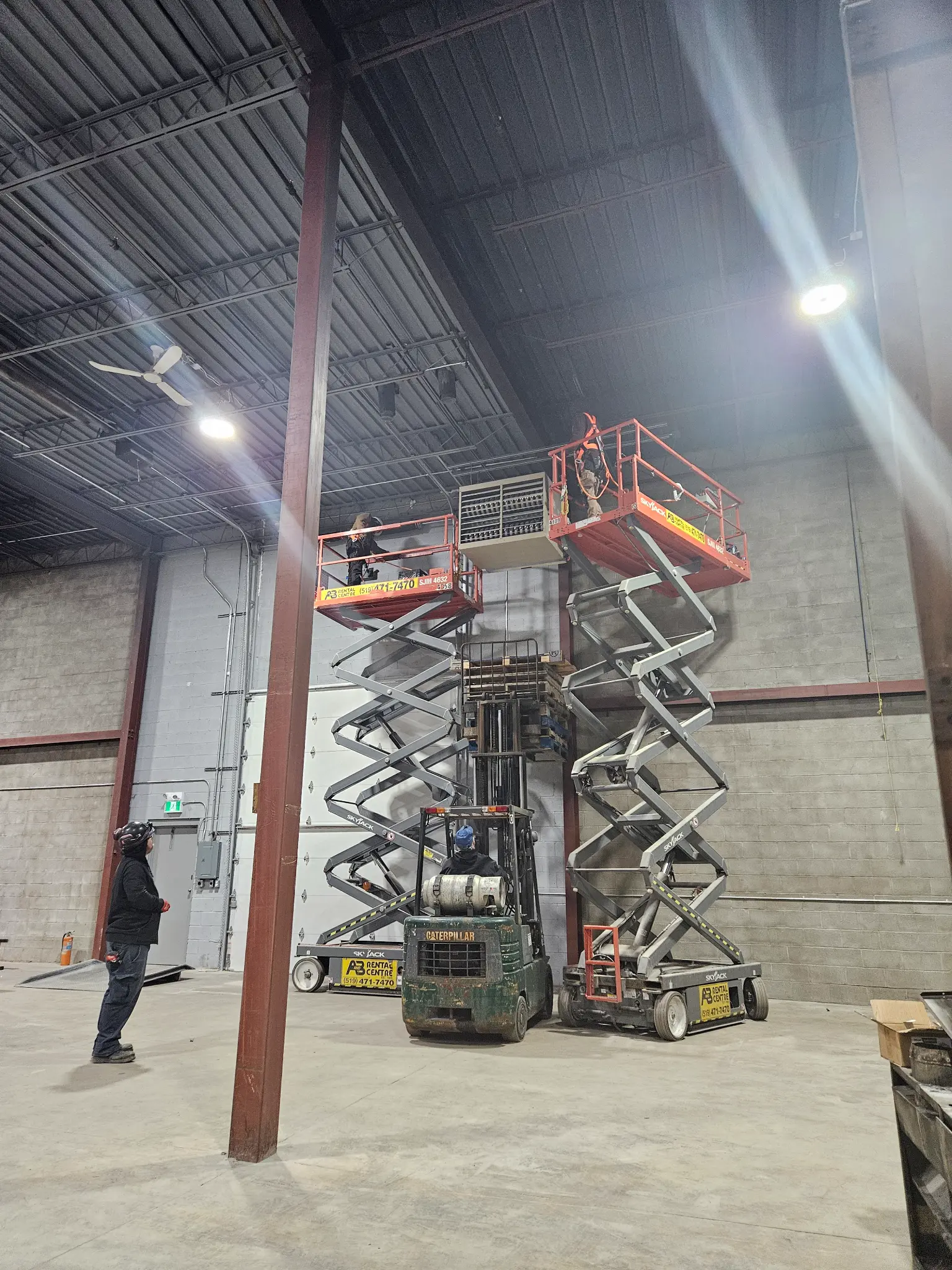 Corner Gas HVAC team on scissor lifts installing a commercial unit heater in a warehouse in London Ontario